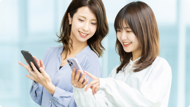 笑顔でスマートフォンを操作する二人の女性