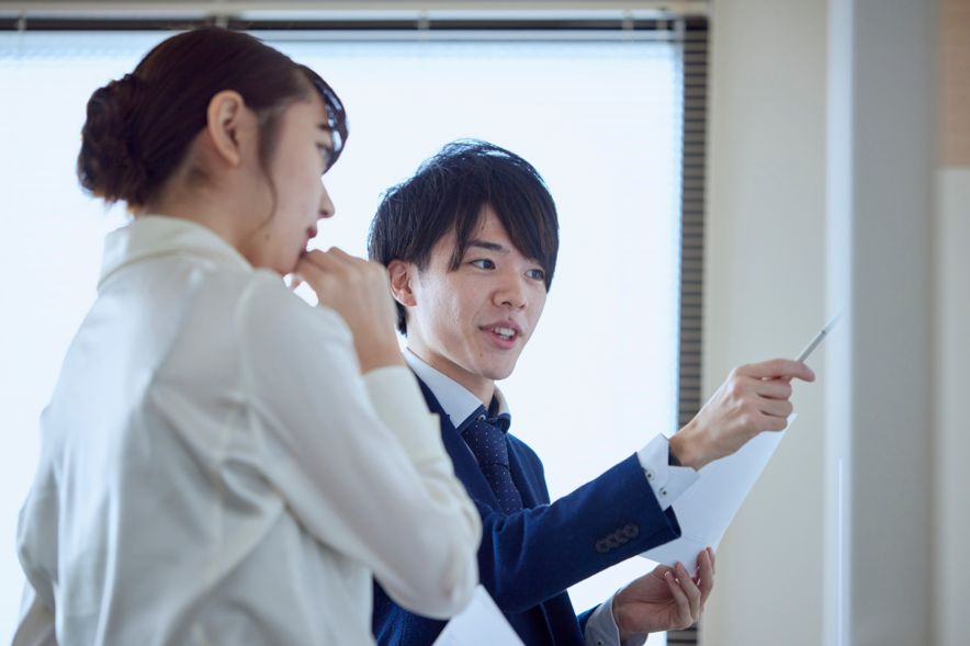 二人でホワイトボードを見ながら考えているイメージ